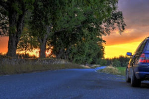 Auto auf einer Landstraße in Schweden bei Sonnenuntergang